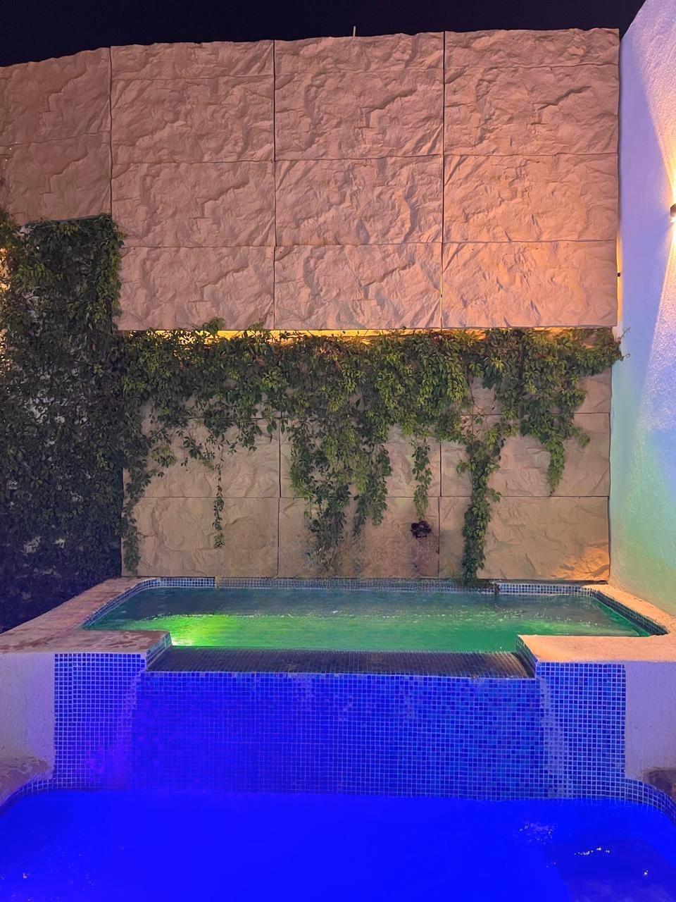 Alberca de relajación iluminada por velas con pétalos flotantes, representando la experiencia de bienestar Nalyjo