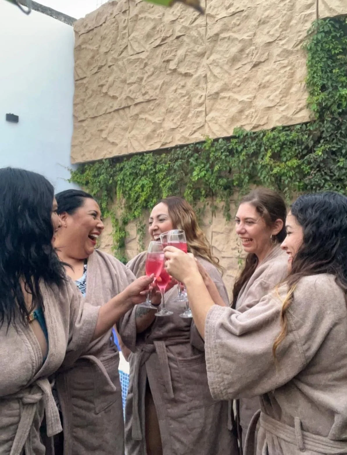 Grupo de clientas disfrutando con batas de spa y brindando en Nalyjo Spa