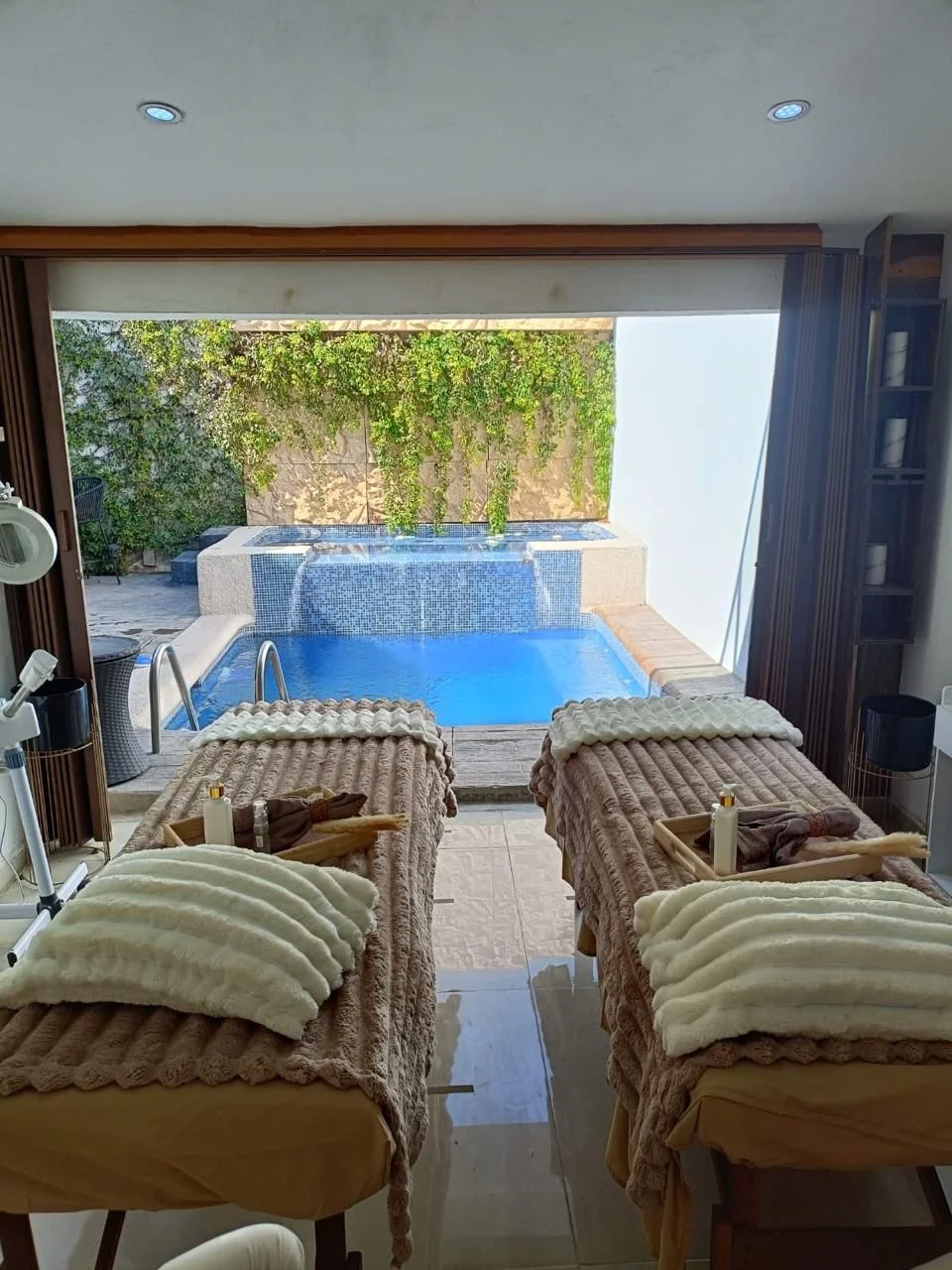 Vista de cabina doble con camillas orientadas hacia la zona de alberca exterior